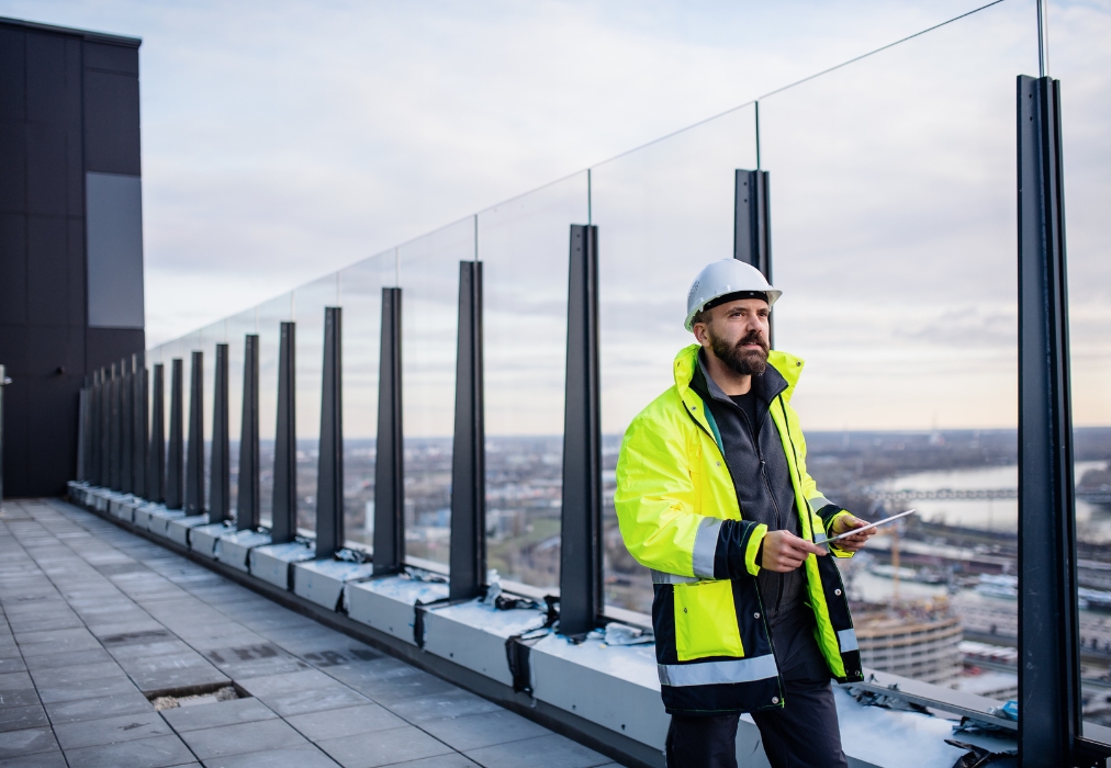 Técnico vestido con ropa de trabajo y casco, mirando desde arriba de un edificio con una vista panorámica de la ciudad